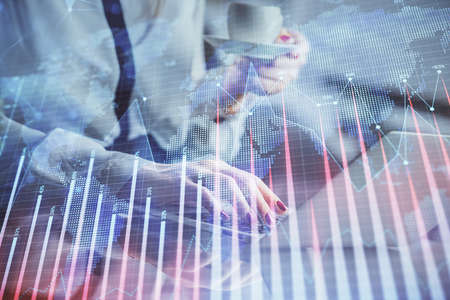Double exposure of businesswoman hands typing on computer and financial graph hologram drawing....