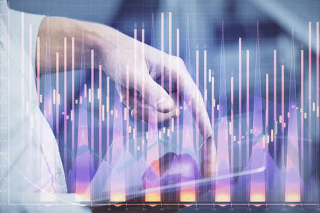 Double exposure of man's hands holding and using a digital device and forex graph drawing. Financial...