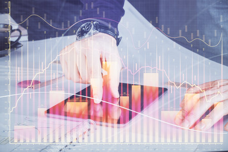 Double exposure of man's hands holding and using a digital device and forex graph drawing. Financial market concept.の写真素材