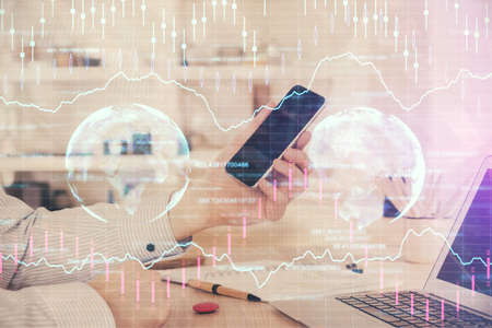 Double exposure of man's hands holding and using a digital device and forex graph drawing. Financial market concept.の写真素材