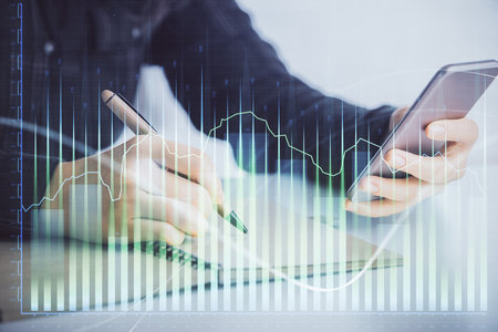 Double exposure of forex graph sketch hologram and woman holding and using a mobile device. Stock market concept.の写真素材