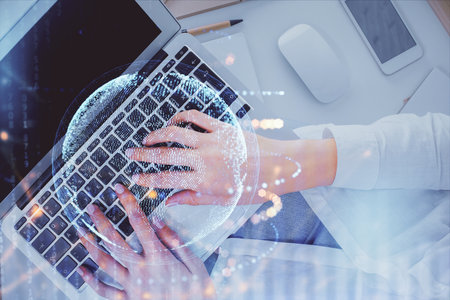 Double exposure of woman hands working on computer and world map hologram drawing. Top View....