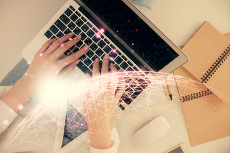 Double exposure of woman hands working on computer and social network theme hologram drawing. Top...