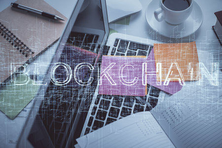 Blockchain theme hologram drawings over computer on the desktop background. Top view. Multi...