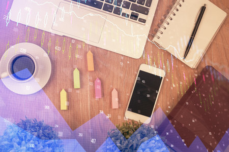 Double exposure of financial chart hologram over desktop with phone. Top view. Mobile trade platform concept.の写真素材