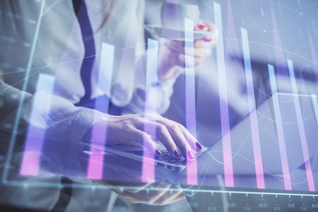Double exposure of businesswoman hands typing on computer and financial graph hologram drawing. Stock market analysis concept.の写真素材