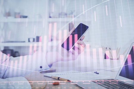 Double exposure of man's hands holding and using a digital device and forex graph drawing. Financial market concept.の写真素材