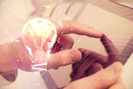 Double exposure of man's hands holding and using a digital device and bulb hologram drawing. Idea concept.の写真素材