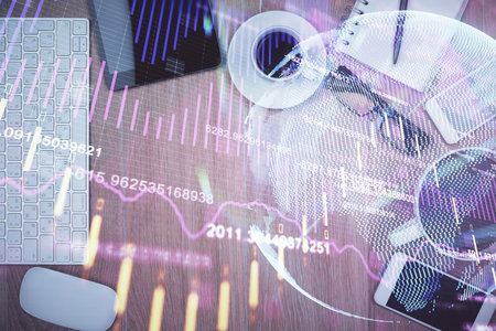 Double exposure of financial chart hologram over desktop with phone. Top view. Mobile trade platform concept.の写真素材