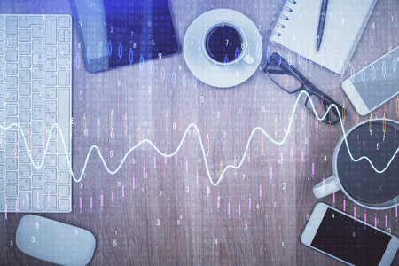 Double exposure of financial chart hologram over desktop with phone. Top view. Mobile trade platform concept.の写真素材