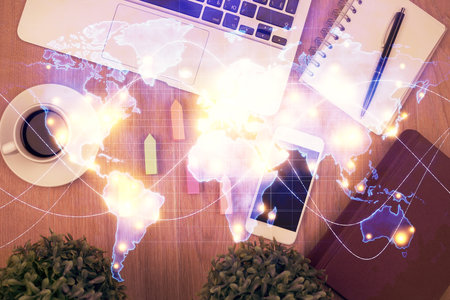 Double exposure of business theme hologram over desktop with phone. Top view. Mobile international...