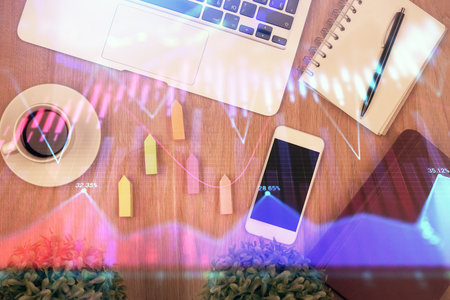 Double exposure of financial chart hologram over desktop with phone. Top view. Mobile trade platform concept.の写真素材