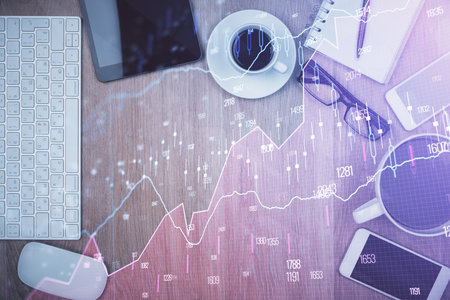 Double exposure of financial chart hologram over desktop with phone. Top view. Mobile trade platform concept.の写真素材