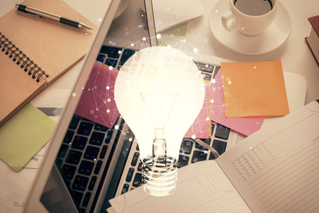 Bulb drawing over computer on the desktop background. Top view. Double exposure. Idea concept.の写真素材