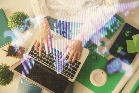Double exposure of woman hands working on computer and financial theme hologram drawing. Top View. Business concept.の写真素材
