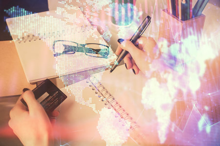 Multi exposure of woman on-line shopping holding a credit card and financial graph drawing. Stock market E-commerce concept.の写真素材
