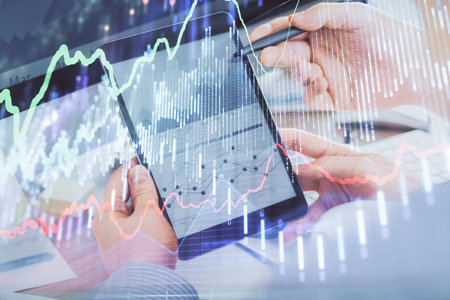 Double exposure of man's hands holding and using a phone and financial chart drawing. Market...