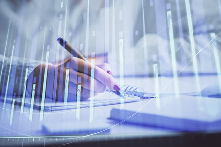 Double exposure of woman's hands making notes with forex graph hologram. Concept stock market analysis.の写真素材