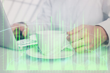 Double exposure of graph with man typing on computer in office on background. Concept of hard work.の写真素材