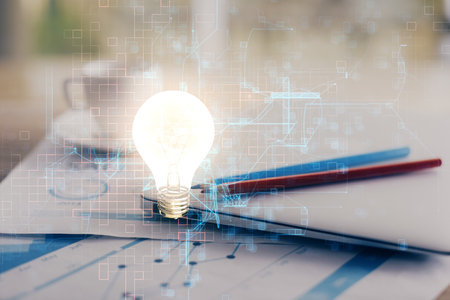 Computer on desktop in office with bulb icon hologram. Double exposure. Concept of idea.の写真素材