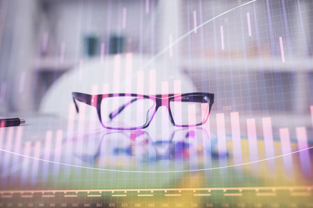 Financial chart hologram with glasses on the table background. Concept of business. Double exposure.の写真素材