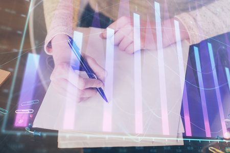 Hands macking notes in notepad. Forex chart holograms in front. Concept of research. Multi exposureの写真素材