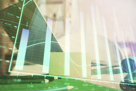 Stock market graph on background with desk and personal computer. Multi exposure. Concept of financial analysis.の写真素材