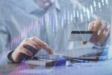 Double exposure of man hands holding a credit card and Forex graph drawing. Stock trading and...