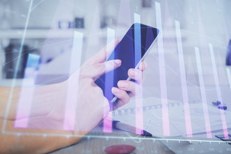 Double exposure of man's hands holding and using a digital device and forex graph drawing. Financial market concept.の写真素材