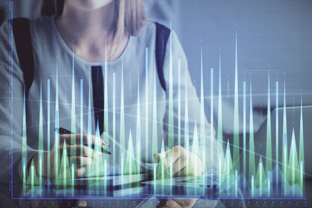 Double exposure of businesswoman hands typing on computer and financial graph hologram drawing. Stock market analysis concept.の写真素材