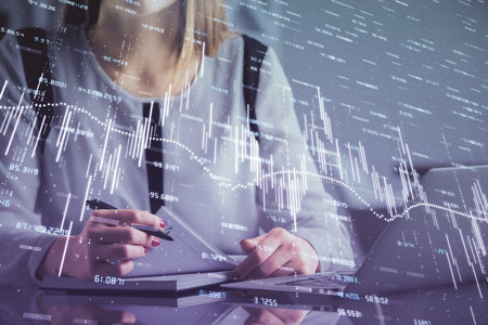 Double exposure of businesswoman hands typing on computer and financial graph hologram drawing. Stock market analysis concept.の写真素材