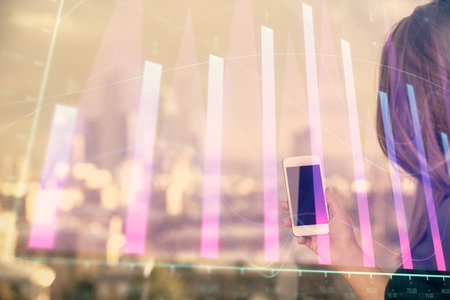 Double exposure of forex chart sketch hologram and woman holding and using a mobile device. Stock market concept.の写真素材