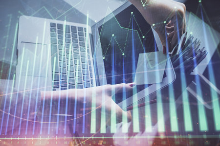 Double exposure of businesswoman hands typing on computer and financial graph hologram drawing. Stock market analysis concept.の写真素材