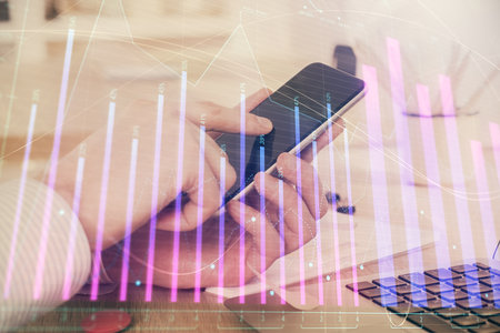 Double exposure of man's hands holding and using a digital device and forex graph drawing. Financial market concept.の写真素材