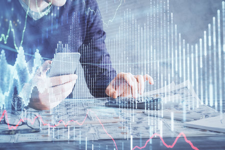 Double exposure of man's hands holding and using a digital device and forex graph drawing. Financial market concept.の写真素材
