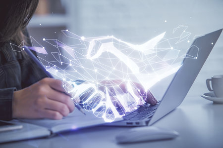Double exposure of woman hands typing on computer and handshake drawing. Partnership concept.の写真素材