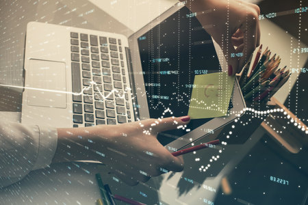 Double exposure of businesswoman hands typing on computer and financial graph hologram drawing. Stock market analysis concept.の写真素材