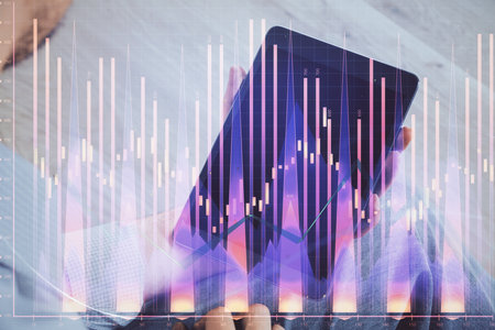 Double exposure of man's hands holding and using a digital device and forex graph drawing. Financial market concept.の写真素材