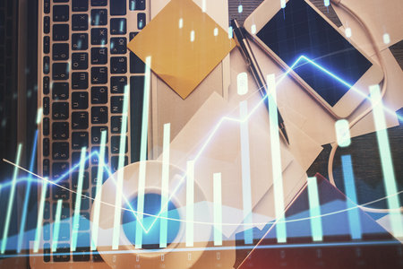Double exposure of financial chart drawing over table background with computer. Concept of research and analysis. Top view.の写真素材