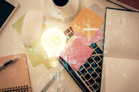 Bulb drawing over computer on the desktop background. Top view. Double exposure. Idea concept.の写真素材