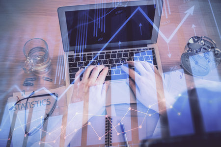 Double exposure of man's hands typing over laptop keyboard and forex chart hologram drawing. Top view. Financial markets concept.の写真素材