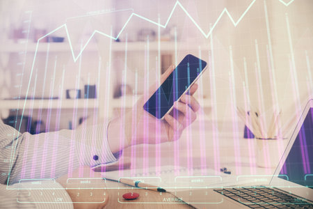 Double exposure of man's hands holding and using a digital device and forex graph drawing. Financial market concept.の写真素材