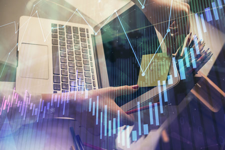 Double exposure of businesswoman hands typing on computer and financial graph hologram drawing. Stock market analysis concept.の写真素材