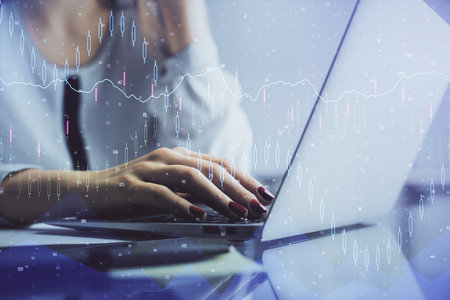 Double exposure of woman hands typing on computer and financial graph hologram drawing. Stock market analysis concept.の写真素材