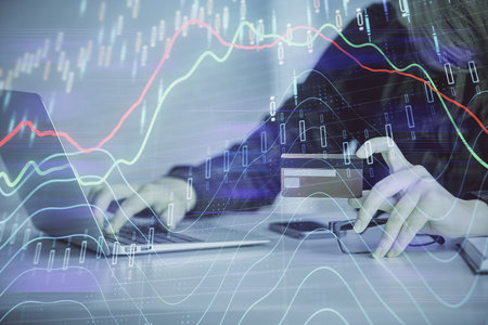 Double exposure of woman on-line shopping holding a credit card and financial graph drawing. Stock market E-commerce concept.の写真素材