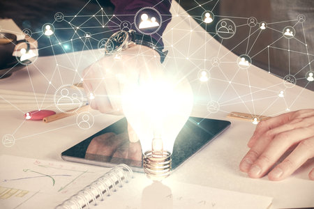 Double exposure of man's hands holding and using a digital device and bulb hologram drawing. Idea concept.の写真素材