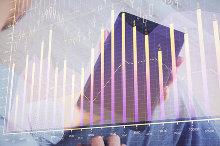 Double exposure of man's hands holding and using a digital device and forex graph drawing. Financial market concept.の写真素材