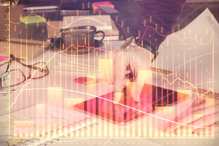 Double exposure of man's hands holding and using a digital device and forex graph drawing. Financial market concept.の写真素材