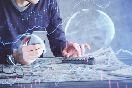 Double exposure of man's hands holding and using a digital device and forex graph drawing. Financial market concept.の写真素材