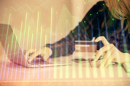 Double exposure of woman on-line shopping holding a credit card and financial graph drawing. Stock market E-commerce concept.の写真素材